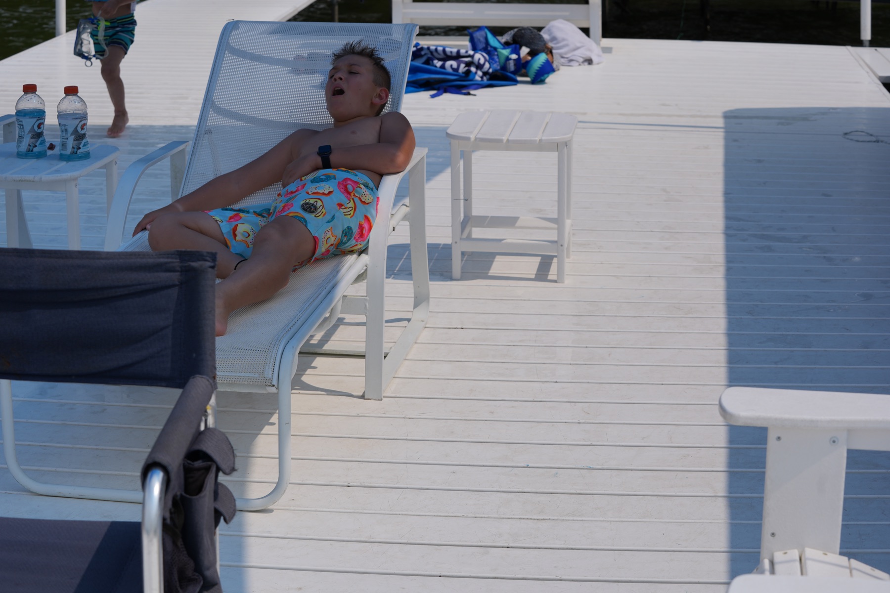 A child resting in a lounge chair beneath the shade